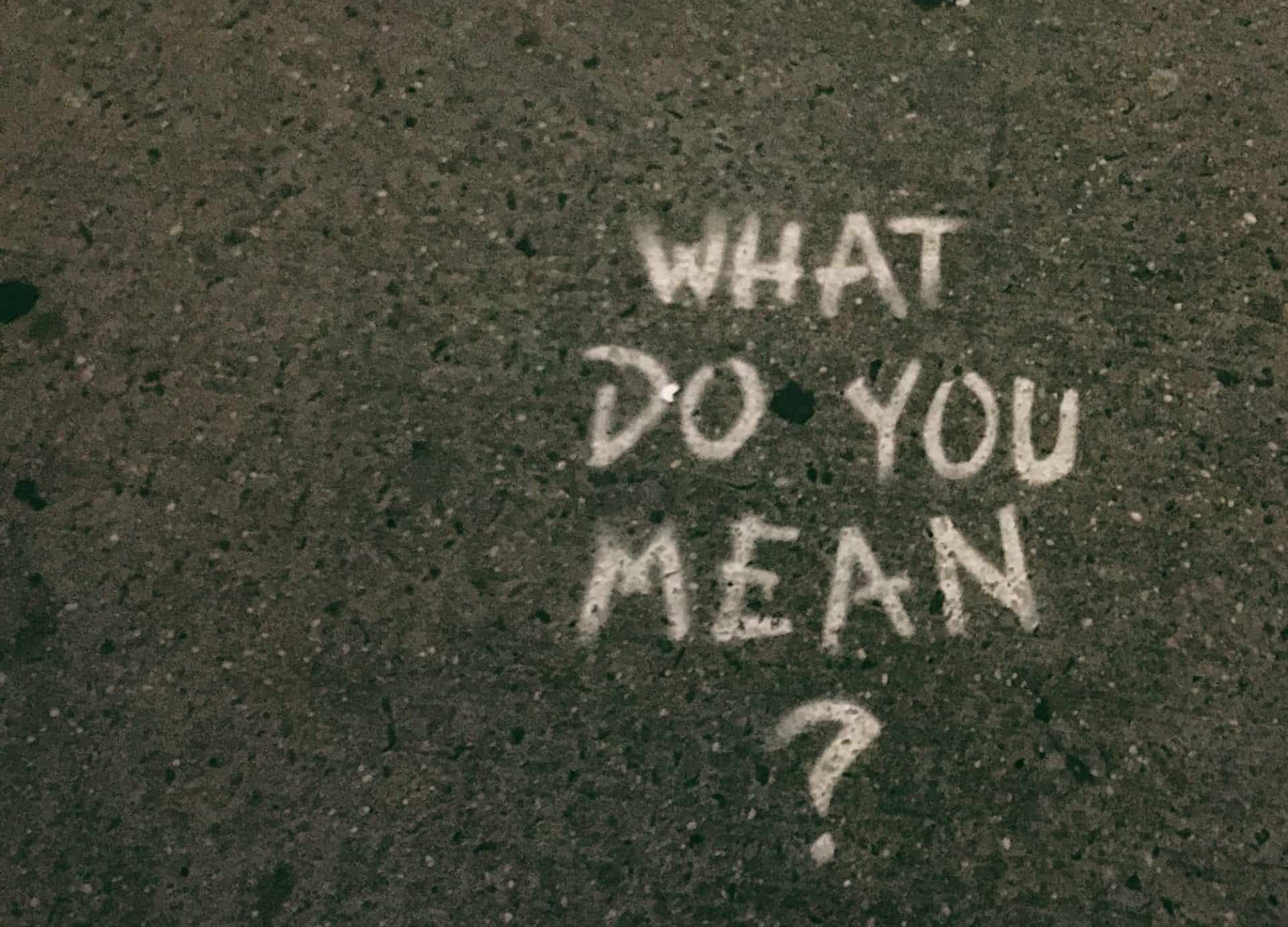 Chalk writing on concrete saying "What do you mean?